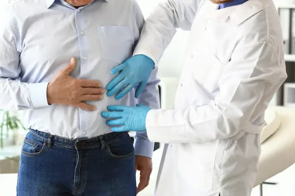 Médico tocando na barriga do paciente para realizar Check-up urológico